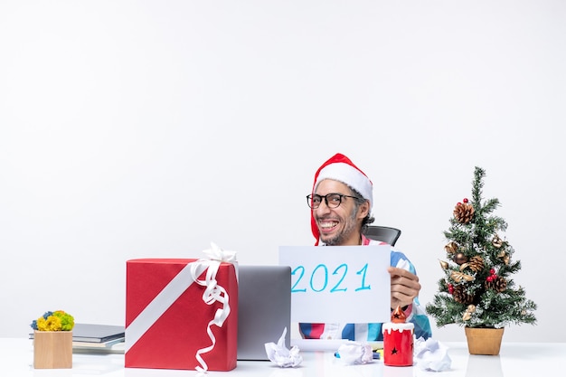 Lavoratore maschio vista frontale seduto nel suo posto di lavoro che tiene nota con la scrittura dell'ufficio di lavoro del nuovo anno natale