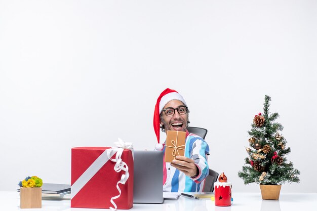 Front view male worker sitting in his working place holding package holidays emotion job christmas business office