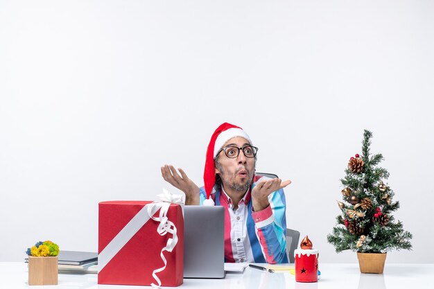Вид спереди мужчина-работник, сидящий на своем рабочем месте в офисе, рождественские деловые эмоции