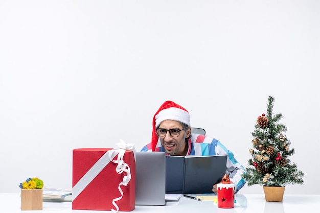 Foto gratuita vista frontale lavoratore maschio seduto nel suo posto di lavoro leggendo quaderno ufficio lavoro affari emozioni natalizie