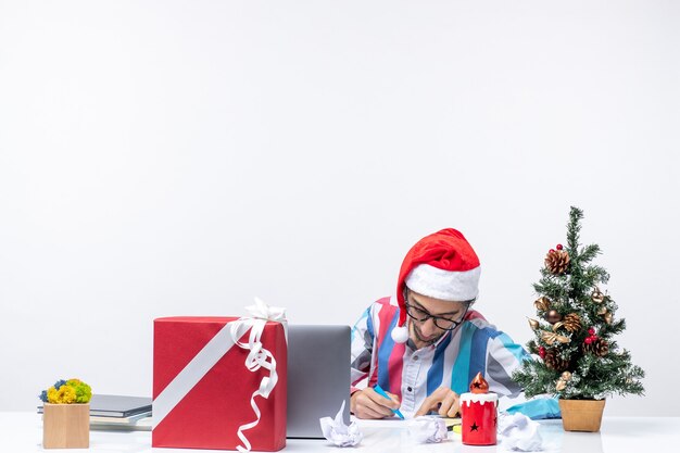 Вид спереди мужчина-работник сидит на своем рабочем месте, пишет заметки, деньги, работа, офис, рождественские эмоции