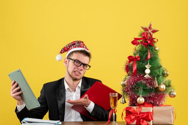 Front view male worker sitting holding note and calculator on yellow 