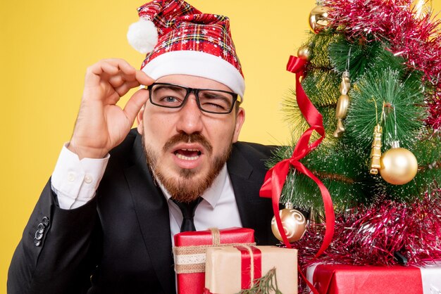 Front view male worker sitting and holding presents on yellow 