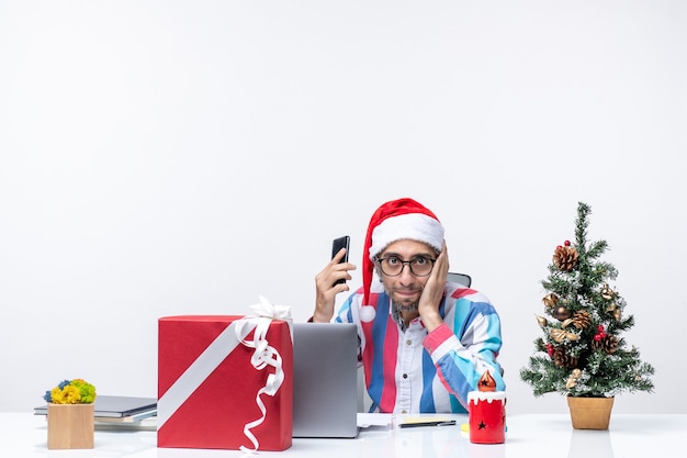 무료 사진 전화 작업 크리스마스 감정 사무실을 들고 노트북과 함께 자신의 자리에 앉아 전면보기 남성 노동자