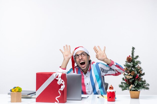 Бесплатное фото Вид спереди мужчина-работник, сидящий на своем рабочем месте, испугался бизнес-рождественской эмоции