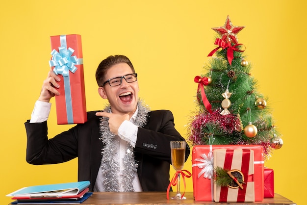 クリスマスプレゼントと一緒に座っている正面図の男性労働者