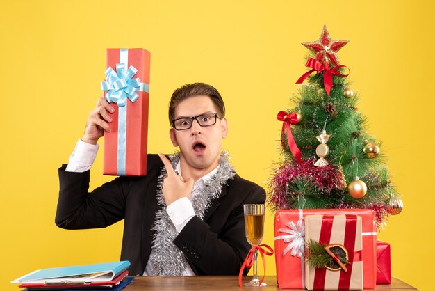 Front view male worker sitting with christmas presents