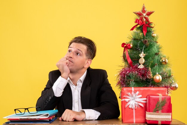 Front view male worker in suit sitting behind his work table stressed