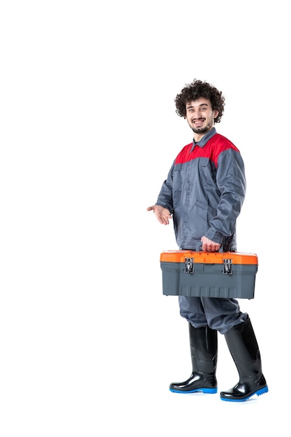 front view male worker in uniform carrying suitcase with tools on white wall