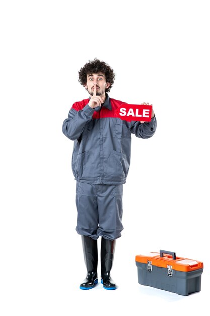 front view of male worker in uniform holding sale nameplate on light wall