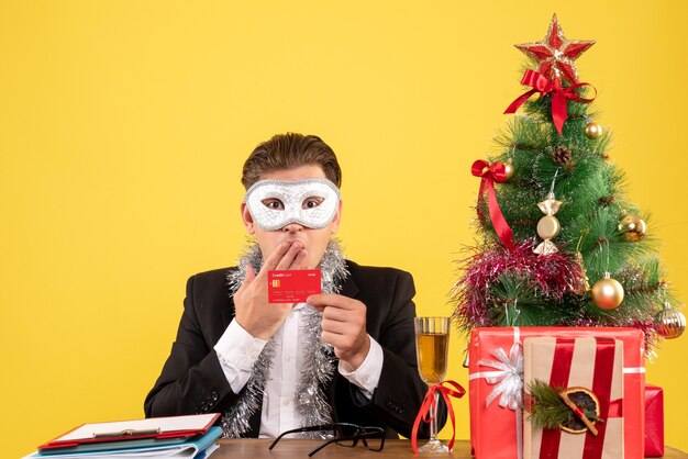 Front view male worker wearing party mask and holding bank card