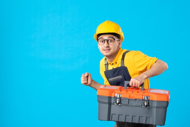 Free photo front view of male worker in yellow uniform with tool box on a blue