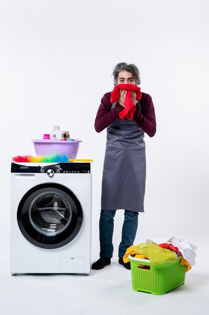 Front view man in apron wiping his face with towel standing near washer on white wall