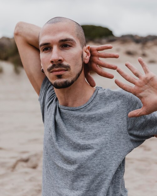 Front view of man on the beach exercising yoga