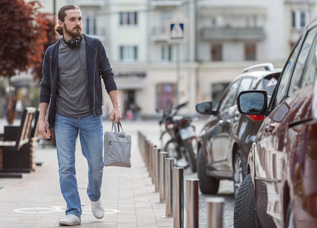 Front view of man in the city carrying laptop bag