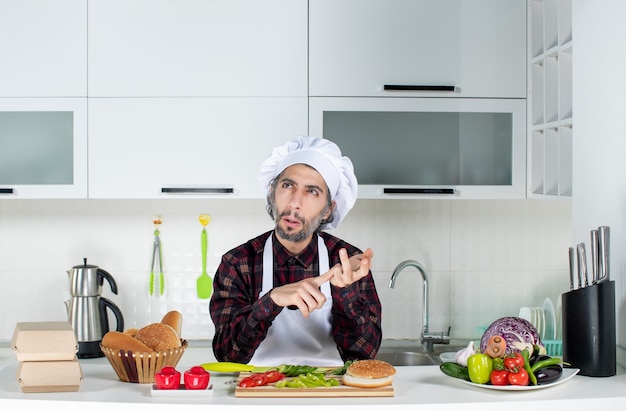 Front view of man in confusion counting something in the kitchen