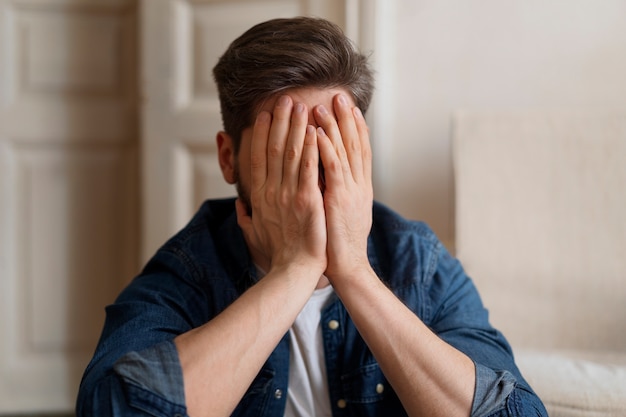 Free photo front view man covering his face