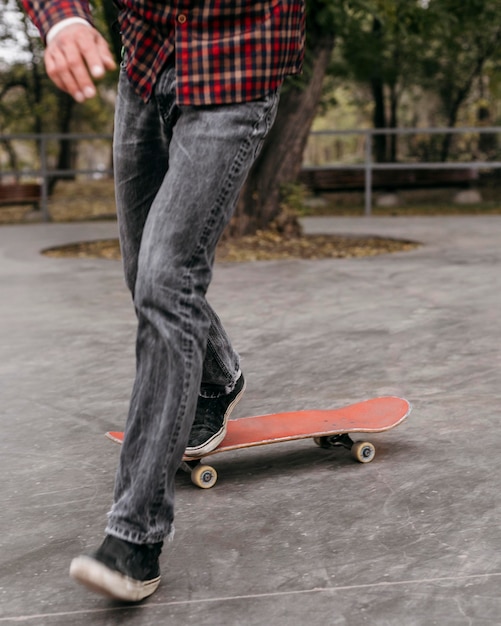Vista frontale dell'uomo che fa i trucchi con lo skateboard fuori nel parco