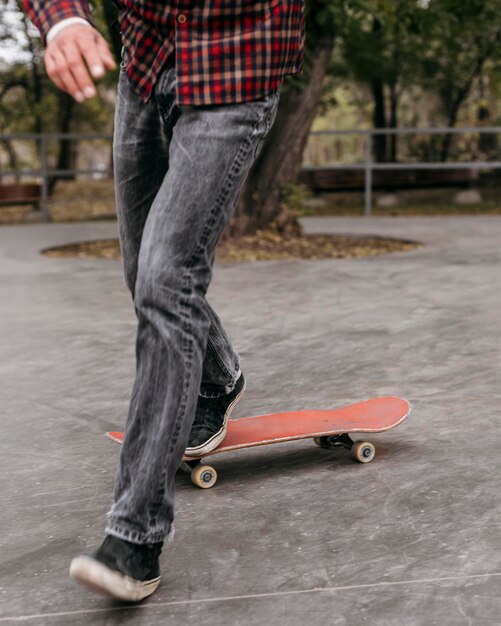 Вид спереди человека, делающего трюки со скейтбордом на улице в парке