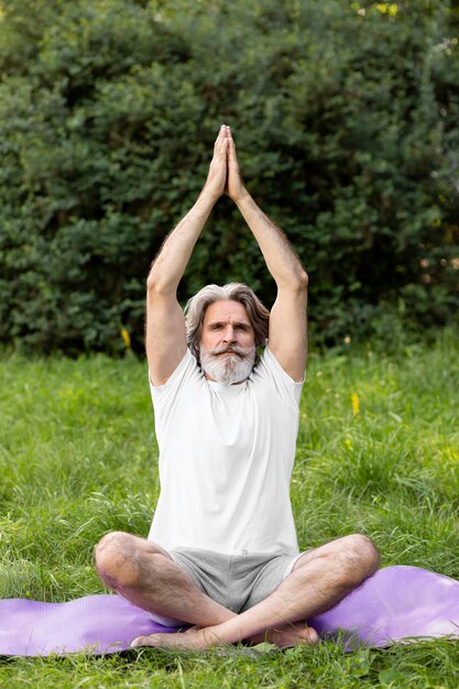 Front view man doing yoga outside