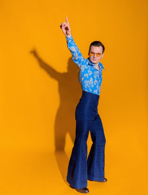 Front view of man dressed in clothing like from 70s on the yellow wall isolated