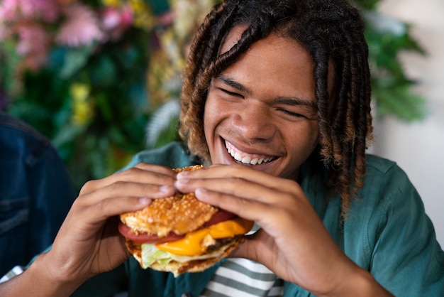 Front view man eating burger in a funny way