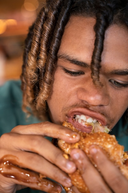 Free photo front view man eating burger in a funny way