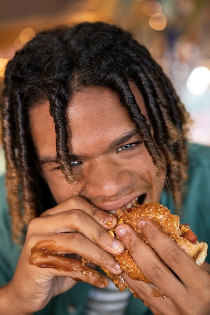 Front view man eating burger in a funny way