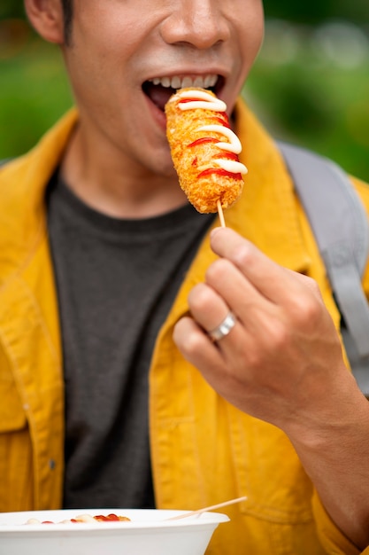 Front view man eating corn dog