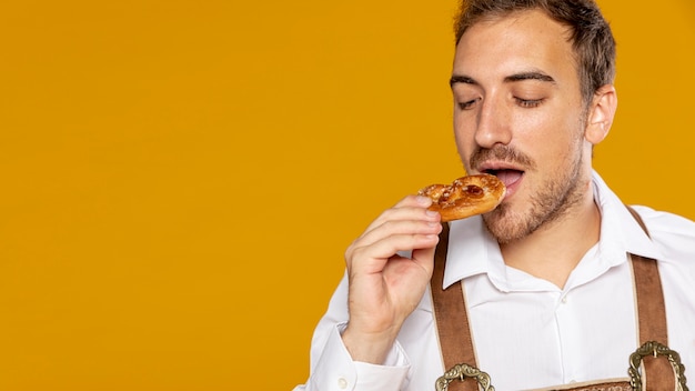 Front view of man eating german pretzel