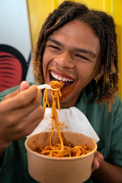 Front view man eating pasta in a funny way