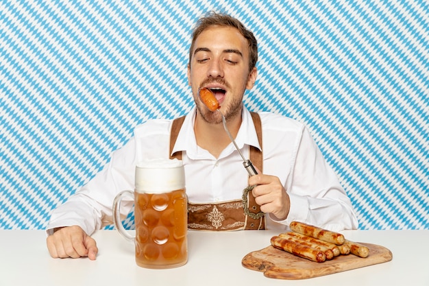 Free photo front view of man eating sausages with beer