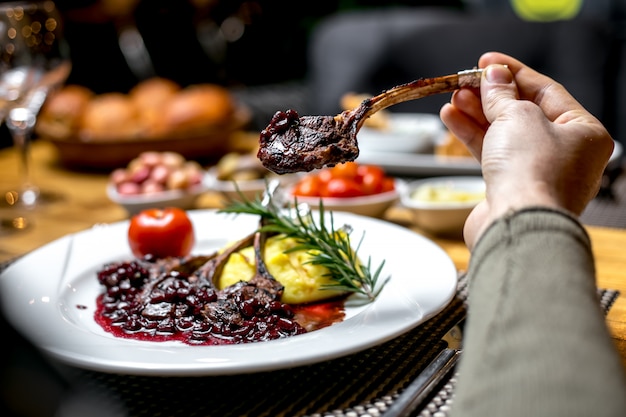 Foto gratuita vista frontale un uomo mangia costolette di agnello fritte in salsa di melograno