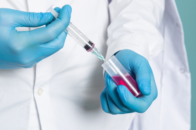 A front view man filling up injection in white medical suit and blue gloves