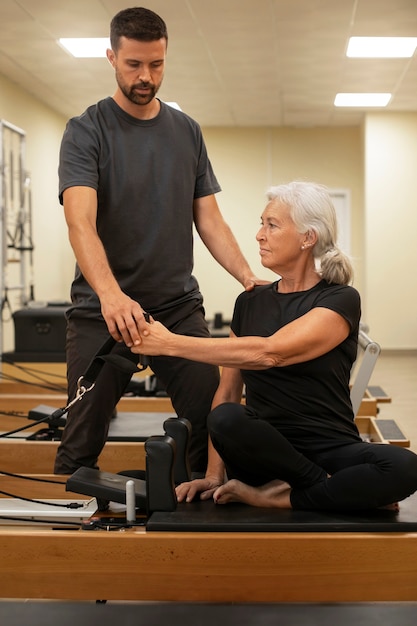 Free photo front view man helping woman in pilates class