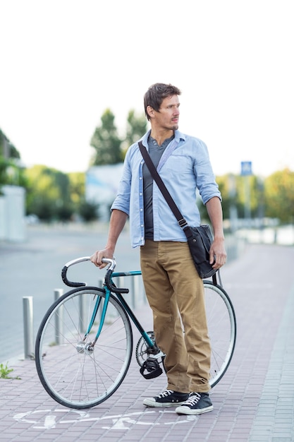 Front view man holding bike outdoors