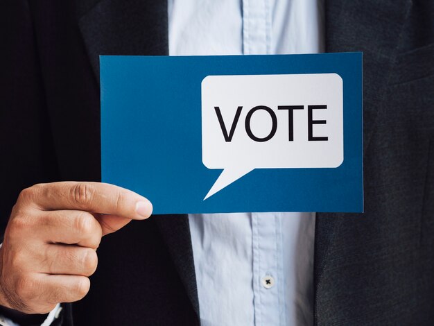 Front view man holding a blue voting speech bubble card