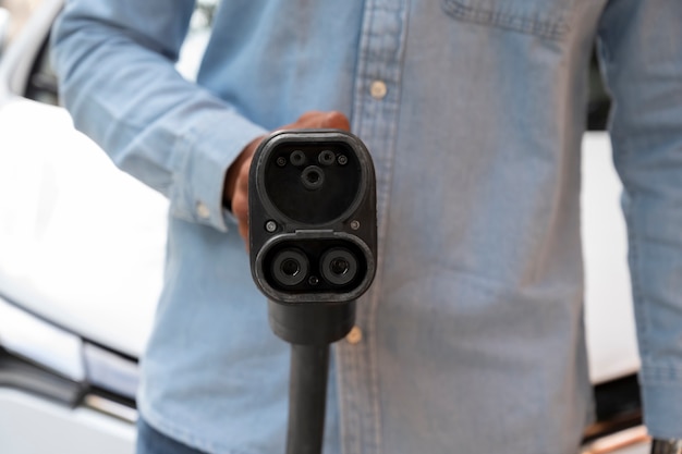 Free photo front view man holding car charger