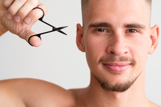 Free photo front view of man holding fingernails scissors