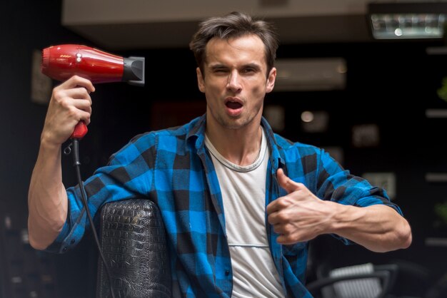 Front view man holding hairdryer