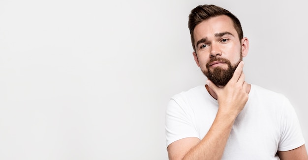 Front view man holding his beard with copy space