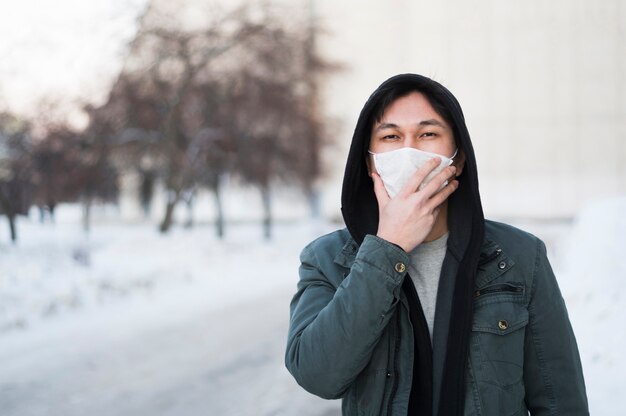 Front view of man holding his medical mask on face while being outside