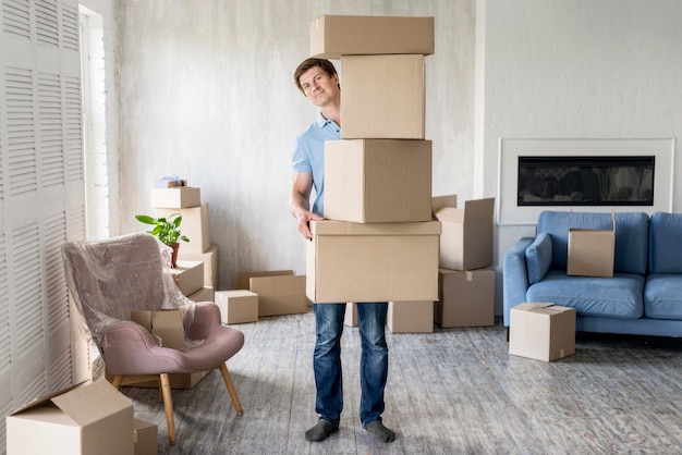 Front view of man holding lots of boxes for moving out