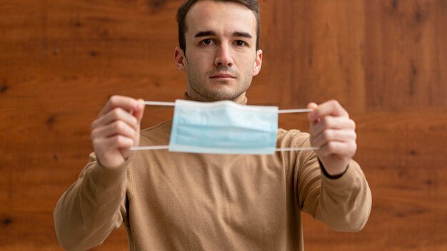 Front view of man holding a medical mask