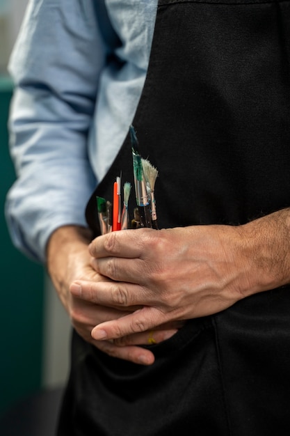 Front view man holding painting brushes