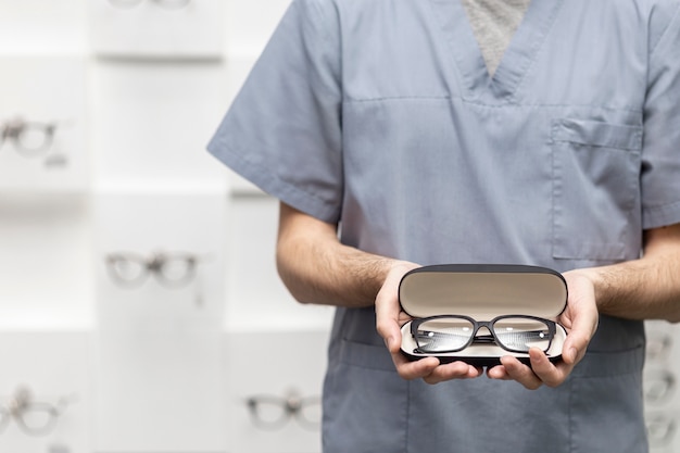 Free photo front view of man holding on pair of glasses in case