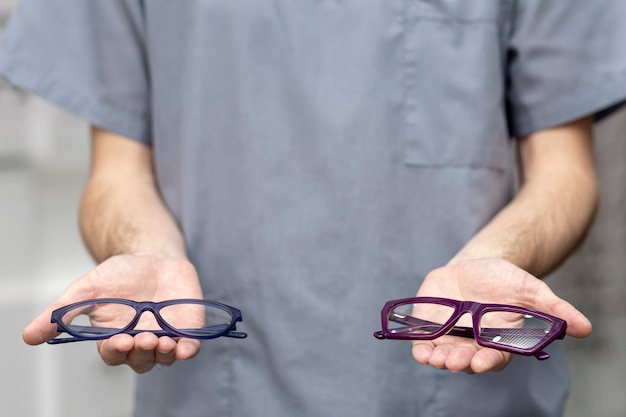 Front view of man holding a pair of glasses in each hand