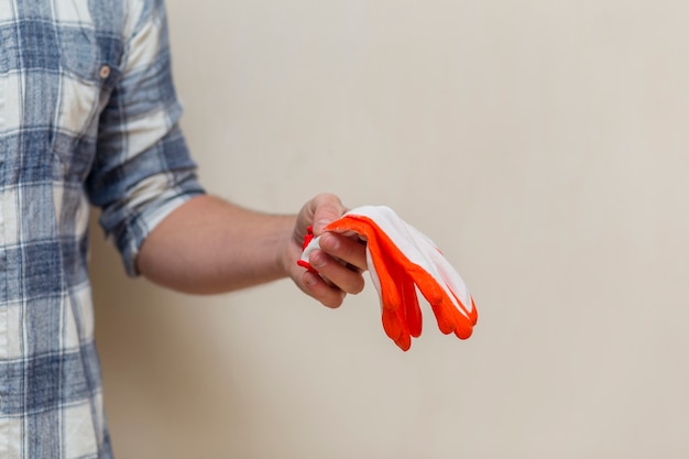 Front view of man holding a pair of gloves