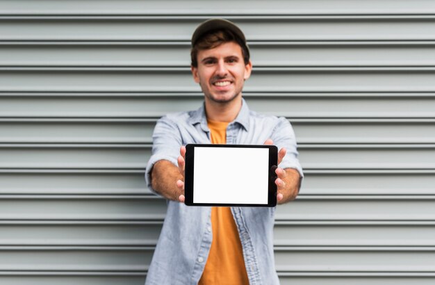 Free photo front view man holding tablet mock-up