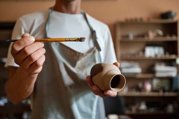 Front view man holding vase and brush